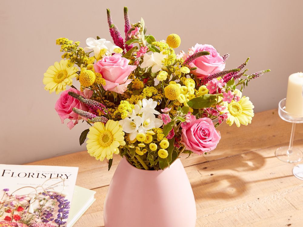 A bouquet of Yellow Tanacetum (painted Daisy), Pink Roses, Pink Oxypetalum, Lemon Germini, White Freesia, Solidago, Pink Veronica, and Craspedia